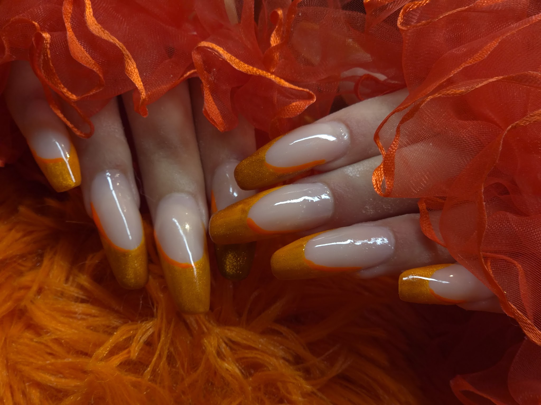 Lange amandelnagels met een oranje French tip, op oranje tule en bont